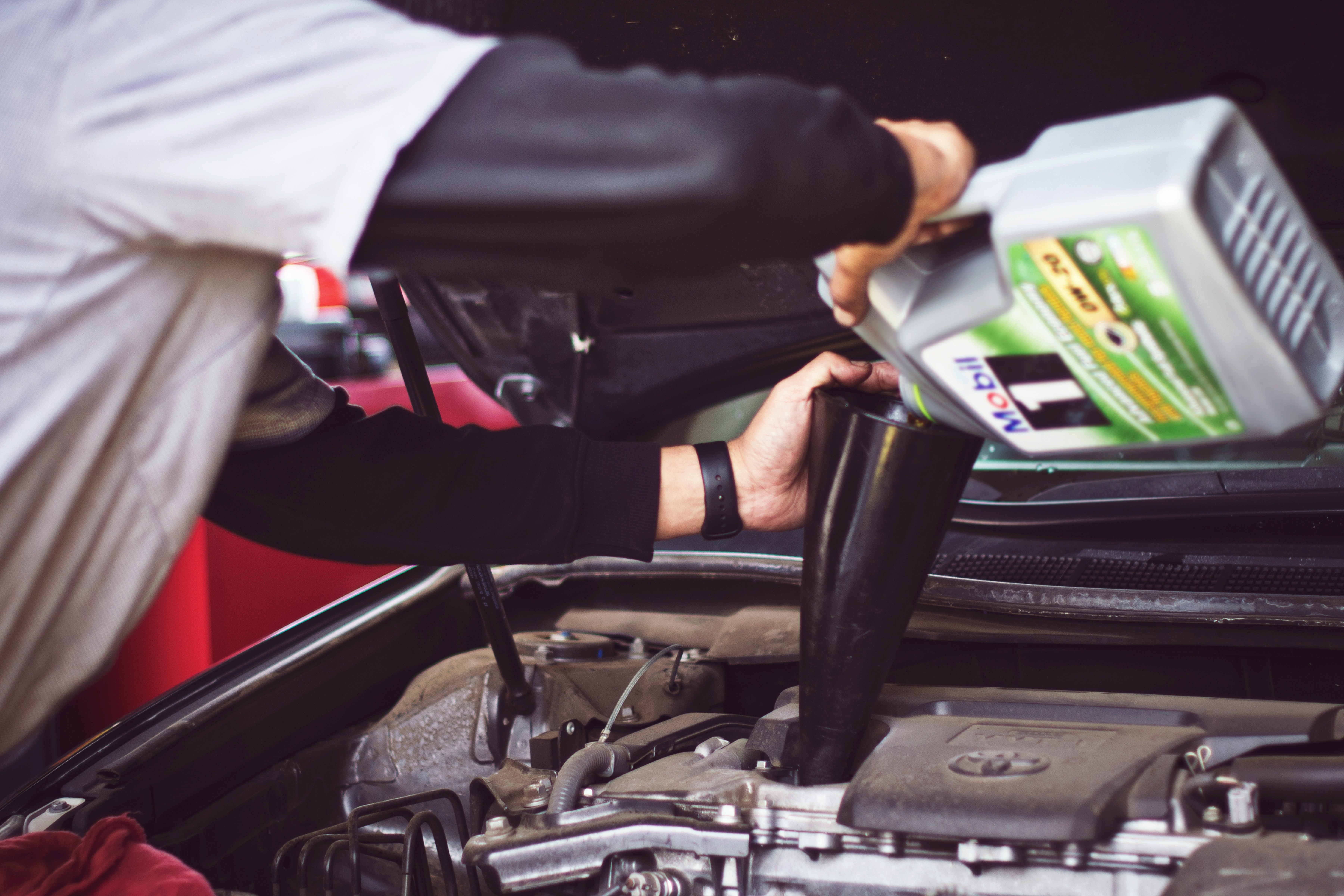 Pouring motor oil into a car engine during an oil change